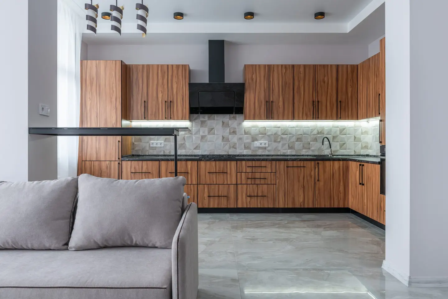 Cocina de madera abierta a un salón, con luz natural y acabados neutros